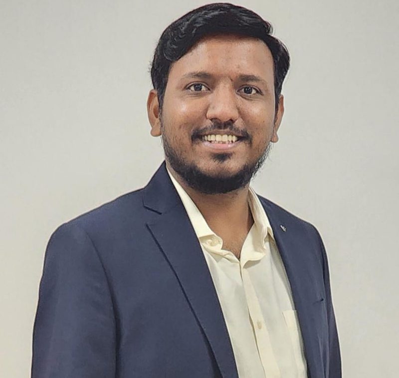 Portrait of a smiling man in a navy blazer and light shirt.